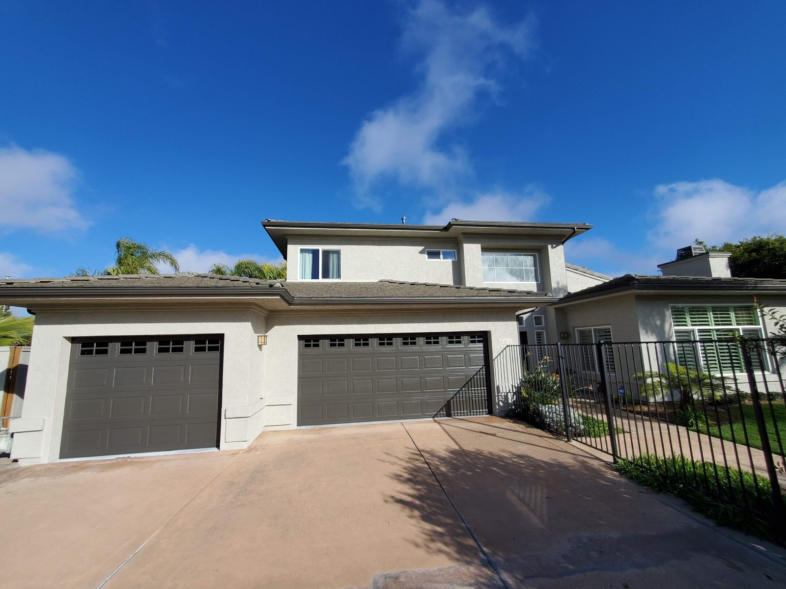 Repainted two storey stucco home with fresh garage doors in San Diego