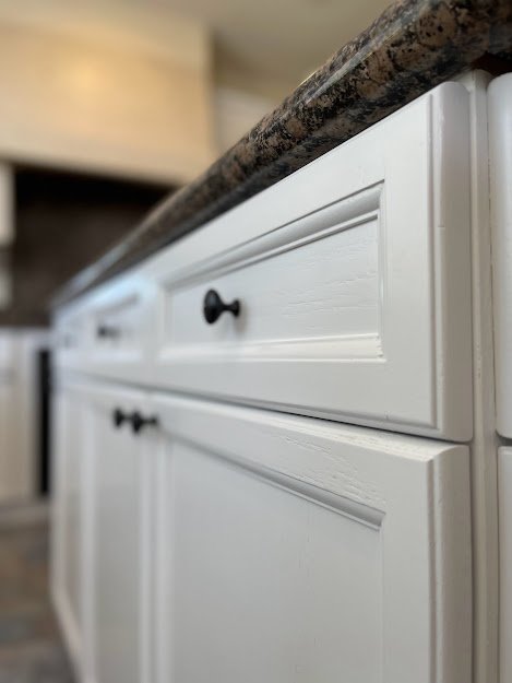 Close up of kitchen cabinet doors freshly refinished in white with black hardware
