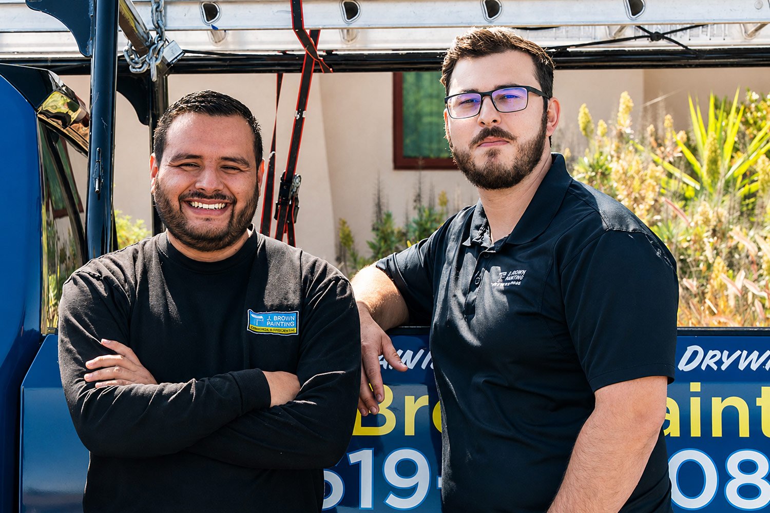 Two J Brown Painting crew members standing in front of a branded company truck